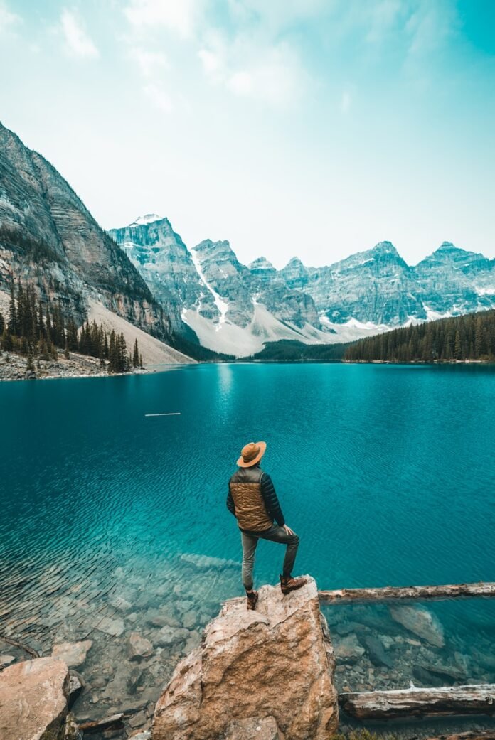 man standing on rock near lake